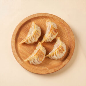 Close-up shot of crispy pre-fried sweet corn and pork gyoza showing the golden pan-fried bottom