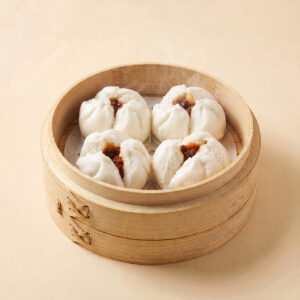 Close-up shot of steaming hot traditional open-top Cantonese BBQ pork bun char siu bao showing savory pork filling