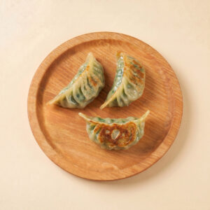 Close-up shot of hot pre-fried pork and chive gyoza highlighting the golden crispy pan-fried bottom crust