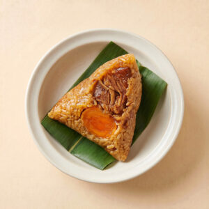 Close-up shot of an unwrapped authentic salted pork and egg yolk zongzi rice dumpling showing rich savory filling