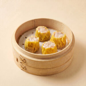 Close-up shot of steaming hot traditional Cantonese golden pork siu mai shumai showing firm meat filling